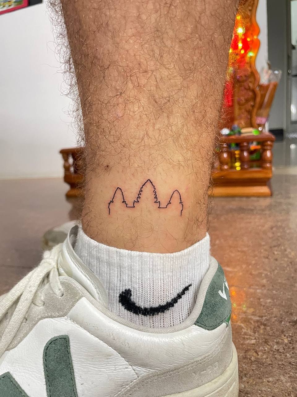 A minimal outline of three Angkor Wat towers above the ankle. Tattoo by Edboi