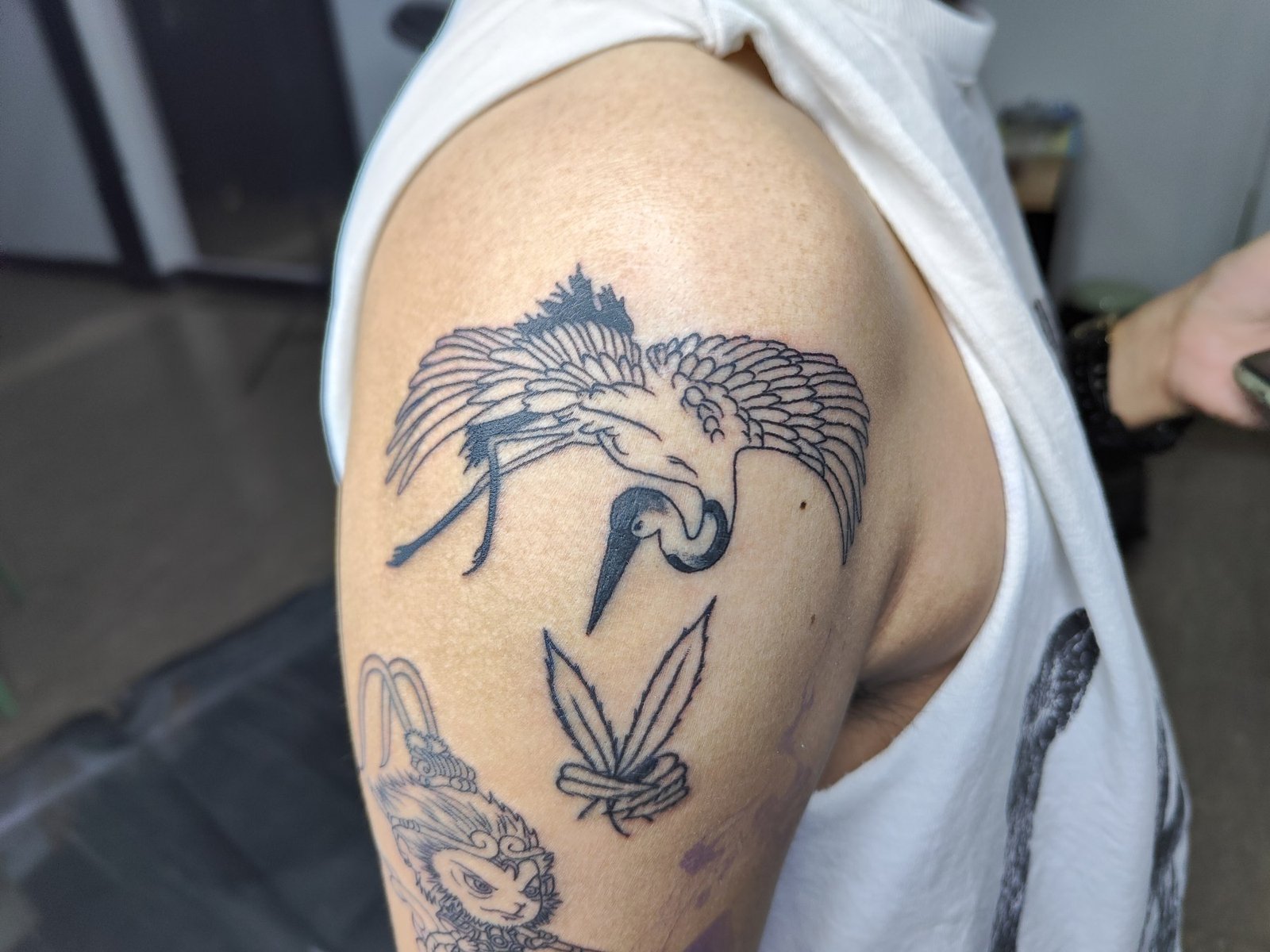 A crane with outstretched wings, fine feather details and bold black accents on the shoulder. Tattoo by Edboi