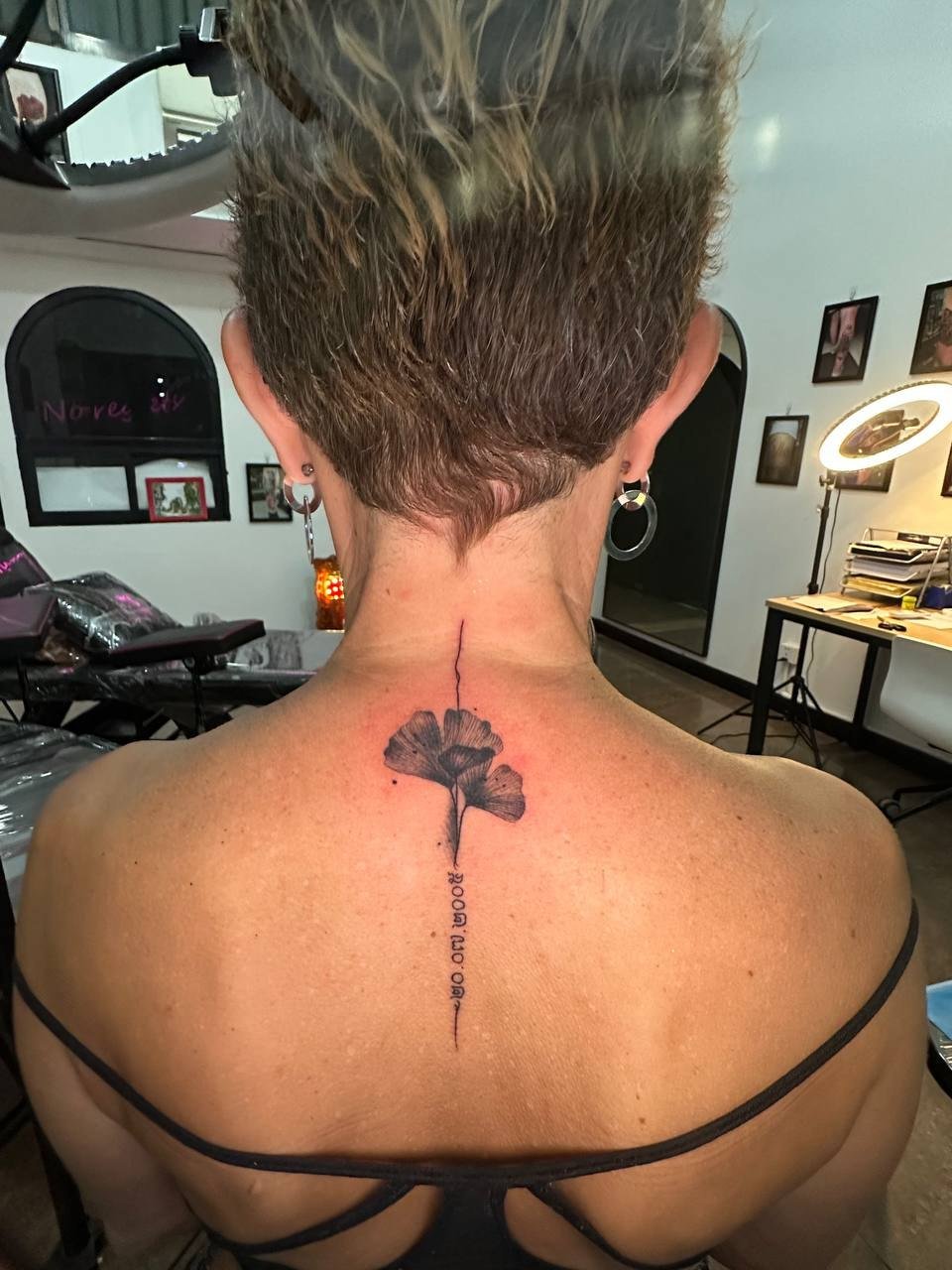 Two shaded fan-shaped ginkgo leaves with vertical lettering on the upper back. Tattoo by Edboi