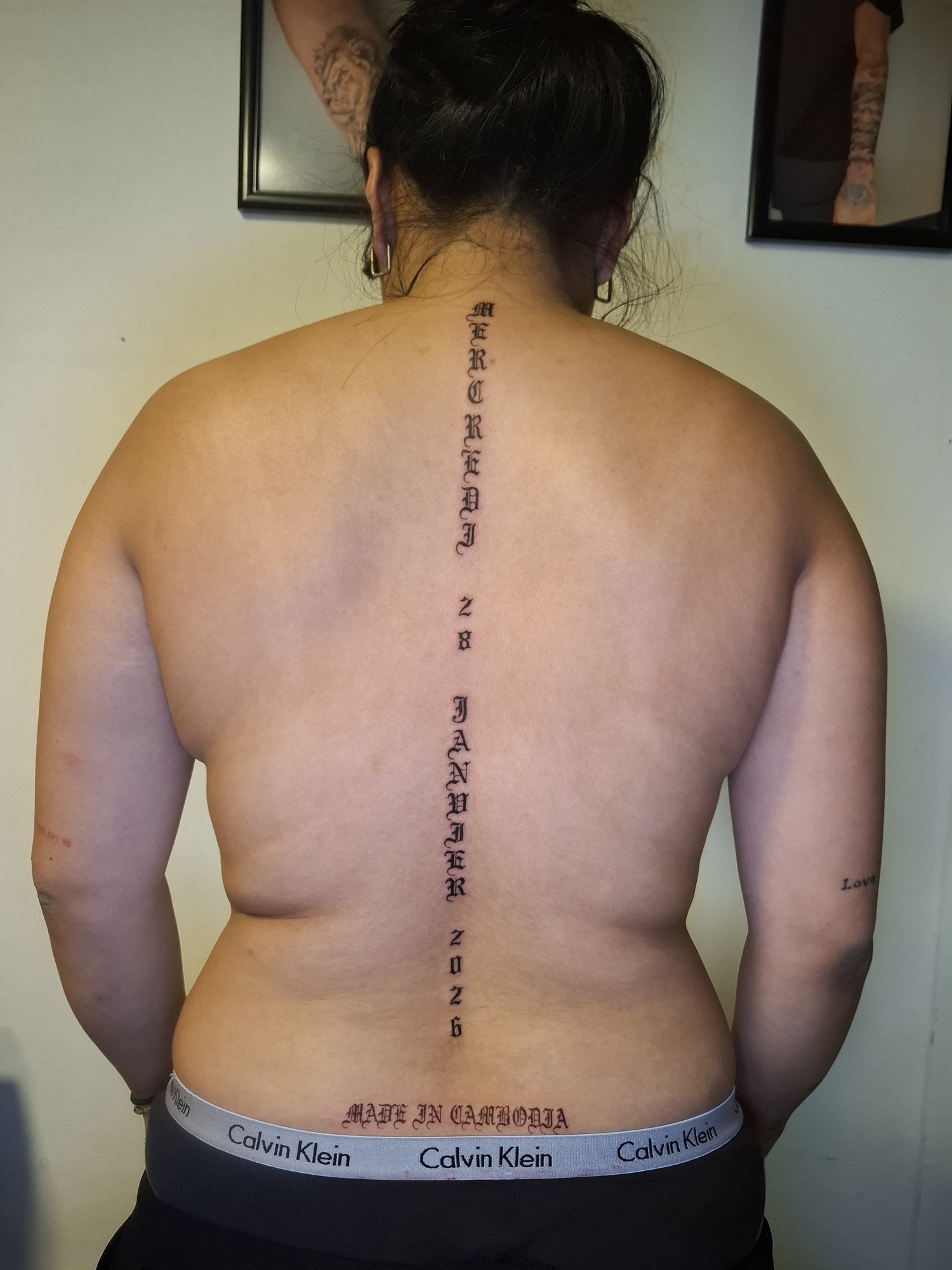 Vertical gothic date lettering down the spine with a separate inscription on the lower back. Tattoo by Edboi