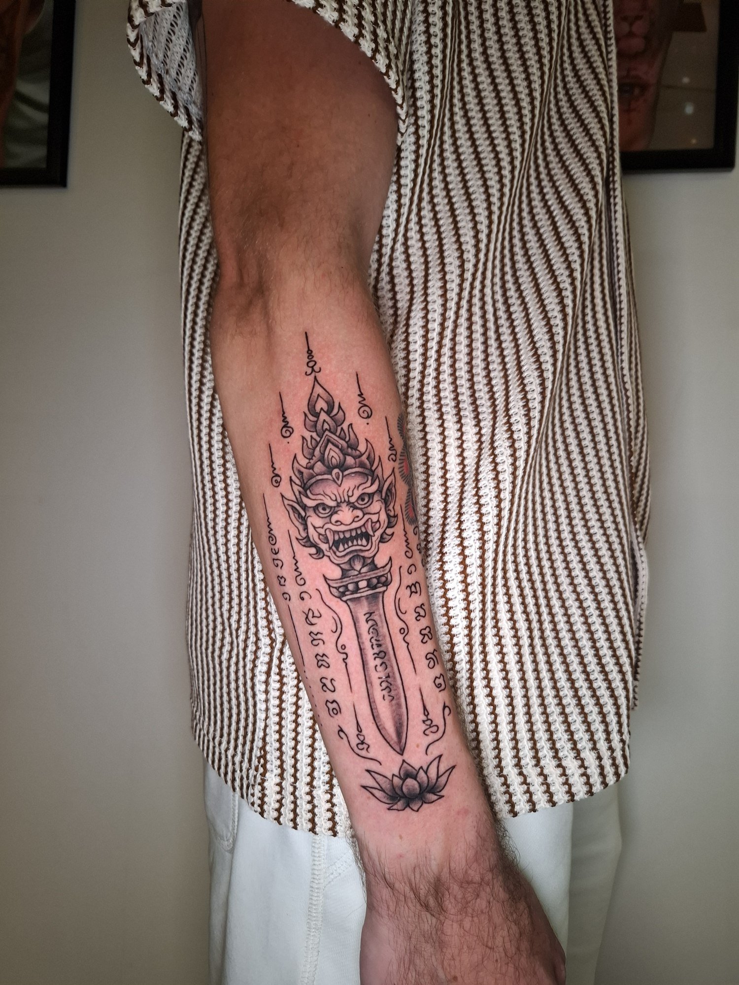 A tall ornamental guardian composition with detailed linework and surrounding script on the arm. Tattoo by Edboi