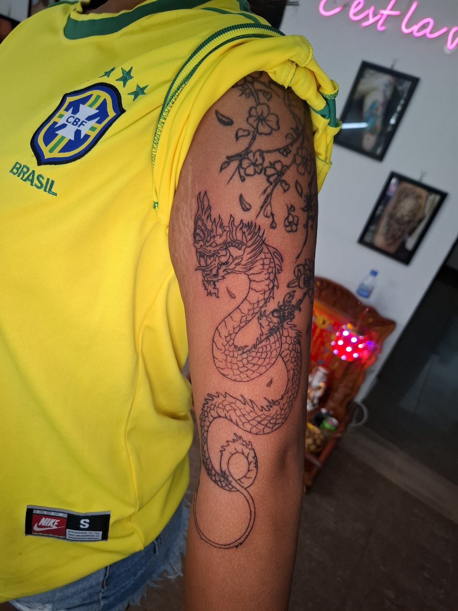A long winding Naga with detailed scales and black linework along the arm. Tattoo by Edboi