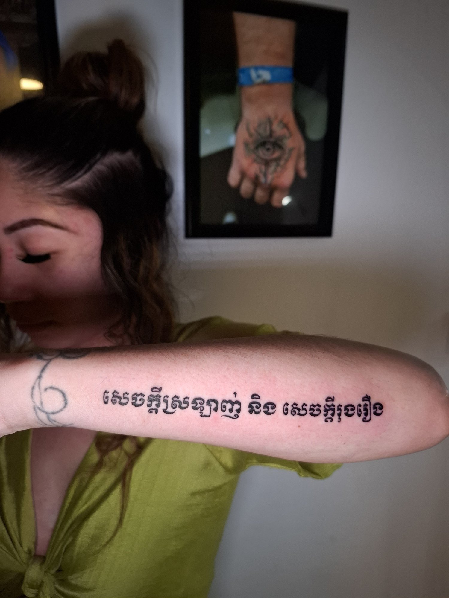 A horizontal line of black Khmer lettering along the inner forearm. Tattoo by Edboi