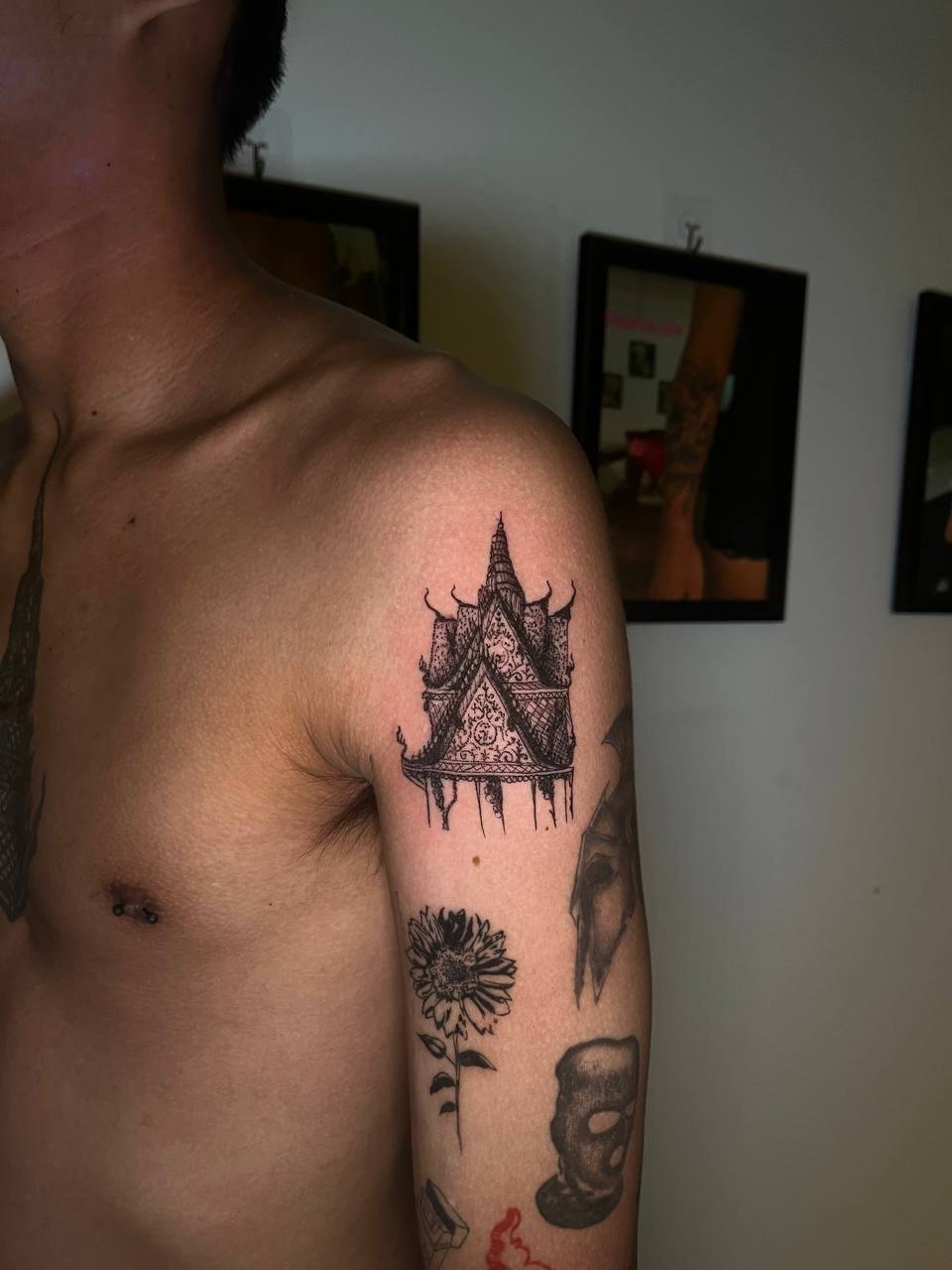 A detailed pointed temple structure in black linework on the upper arm. Tattoo by Edboi