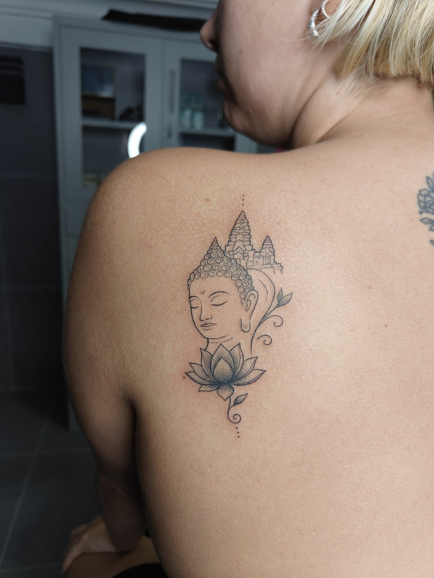 A softly shaded Buddha face with lotus petals and ornamental details on the upper back. Tattoo by Edboi