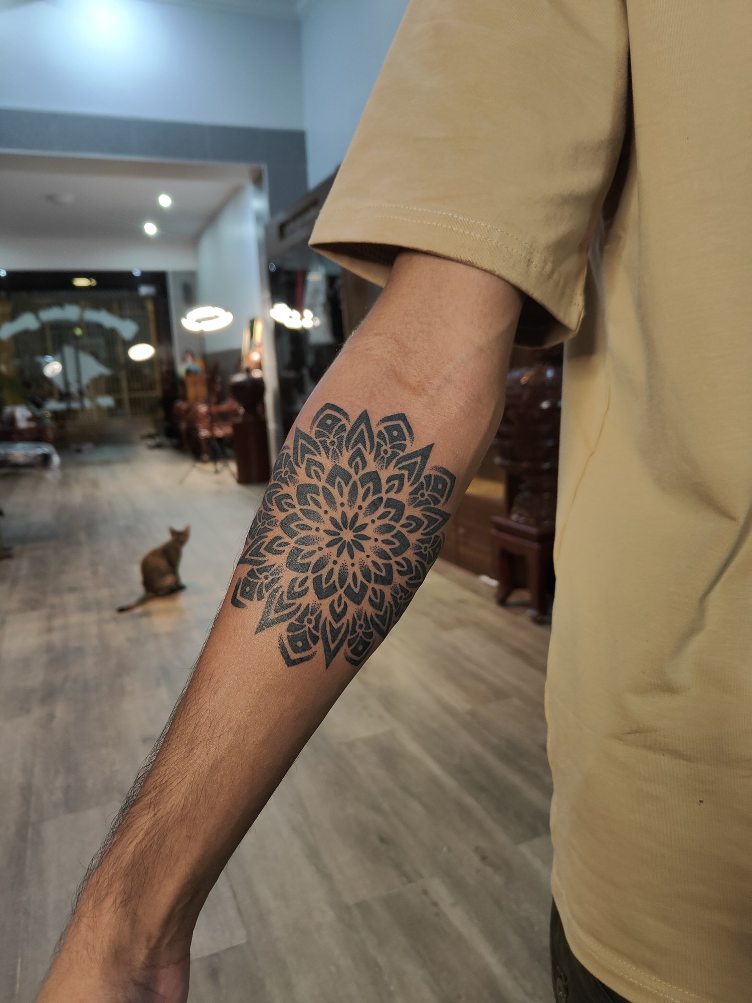 A large detailed floral mandala in black linework and shading on the forearm. Tattoo by Edboi