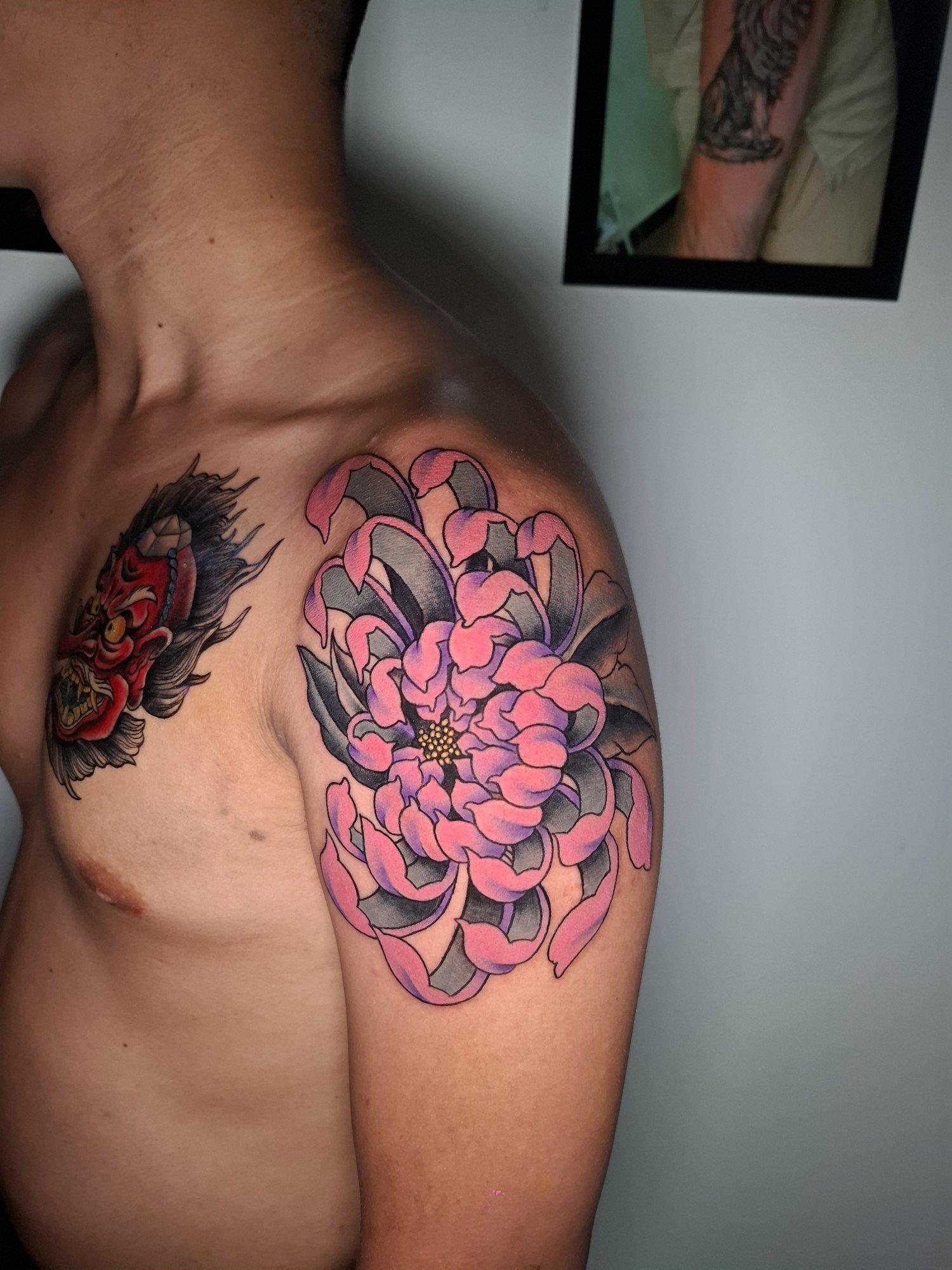 A large pink and purple chrysanthemum with black and grey shading on the shoulder. Tattoo by Edboi
