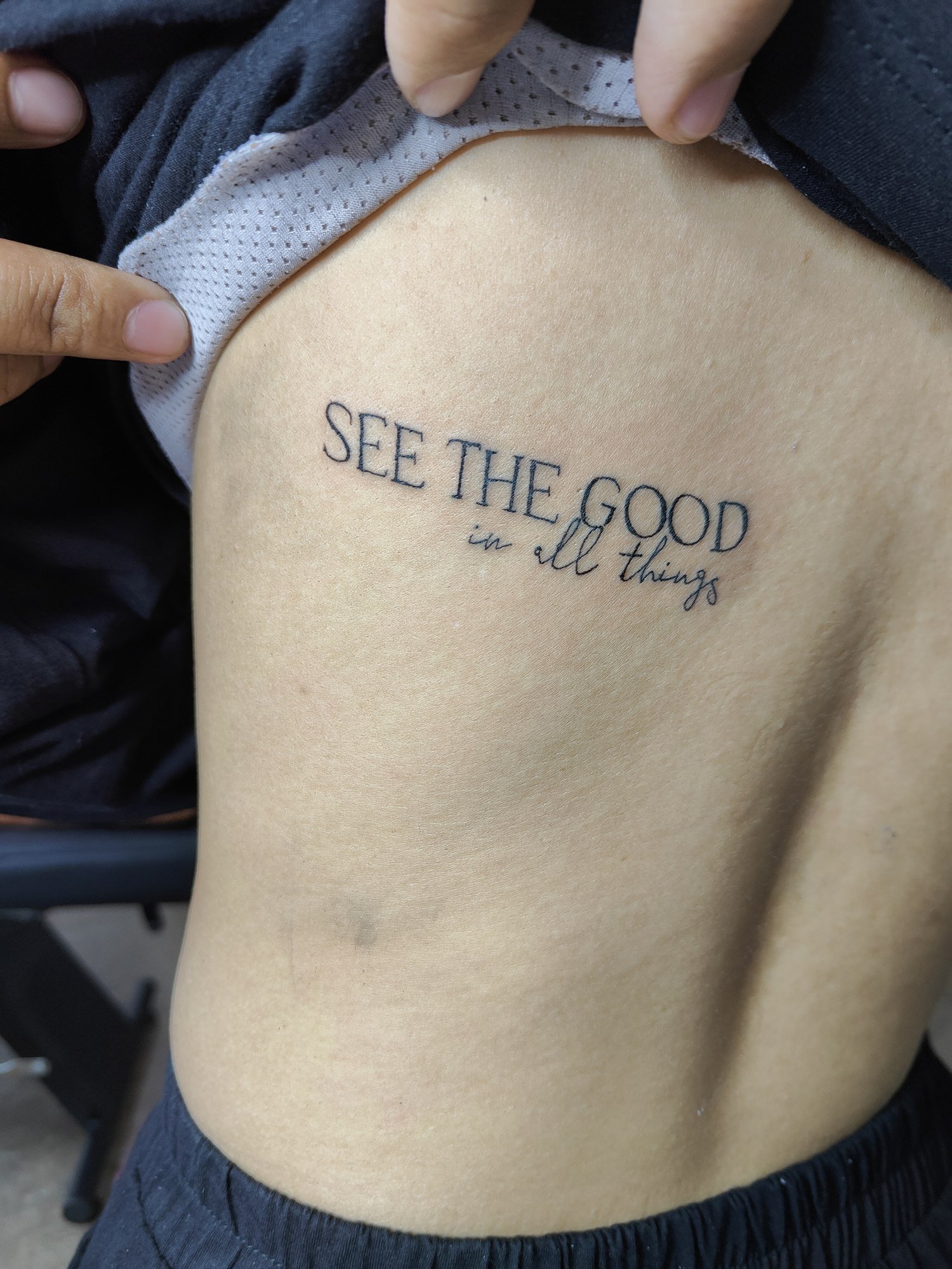 Fine black capital letters paired with small cursive lettering on the ribs. Tattoo by Edboi