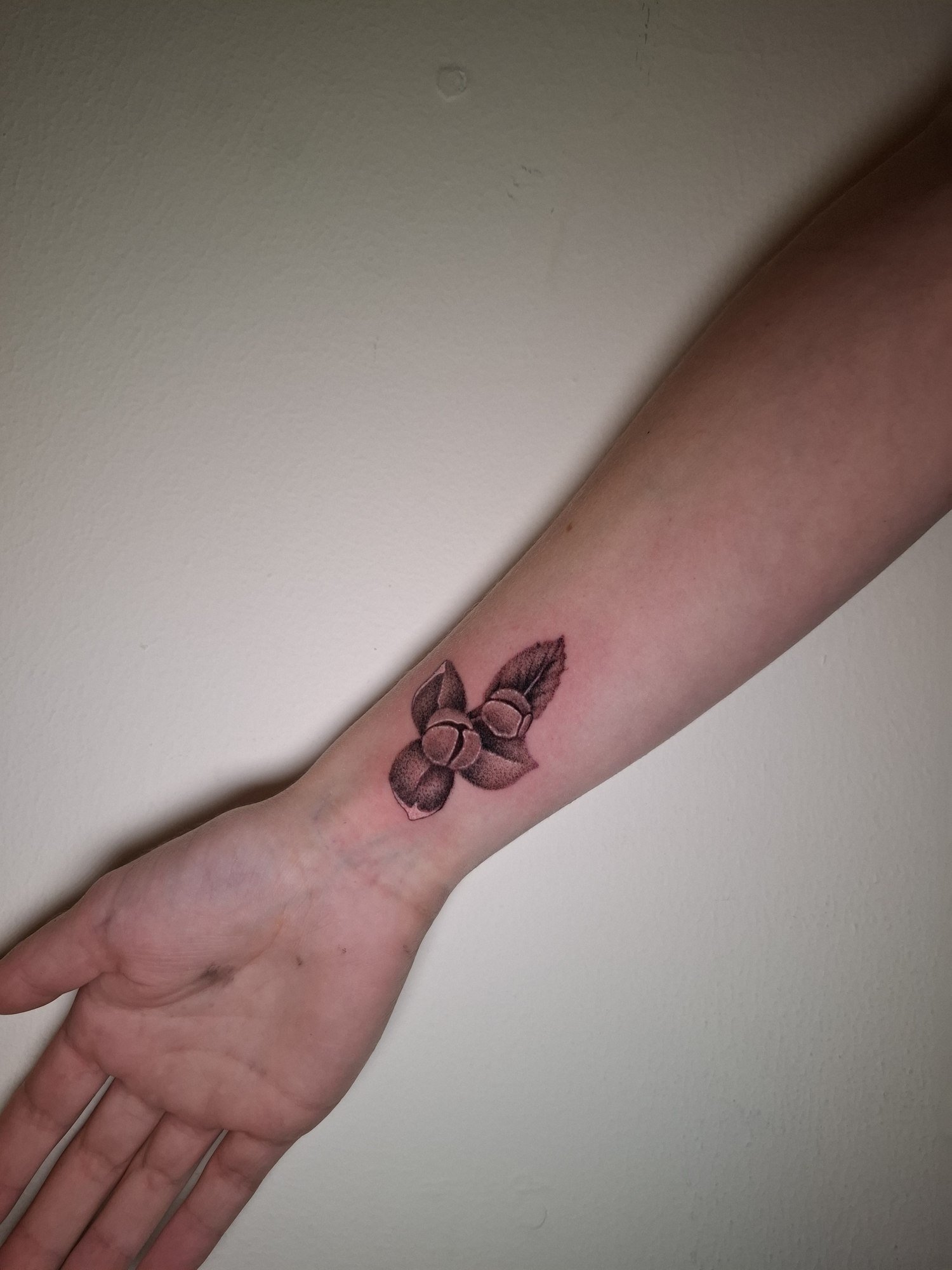 A small flower with softly shaded petals and a leaf on the inner wrist. Tattoo by Edboi