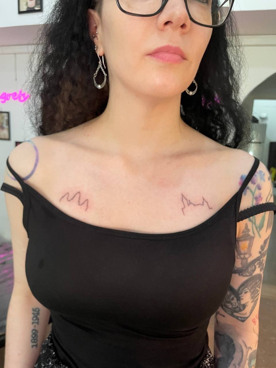 Two minimal temple outlines placed beneath the collarbones. Tattoo by Edboi