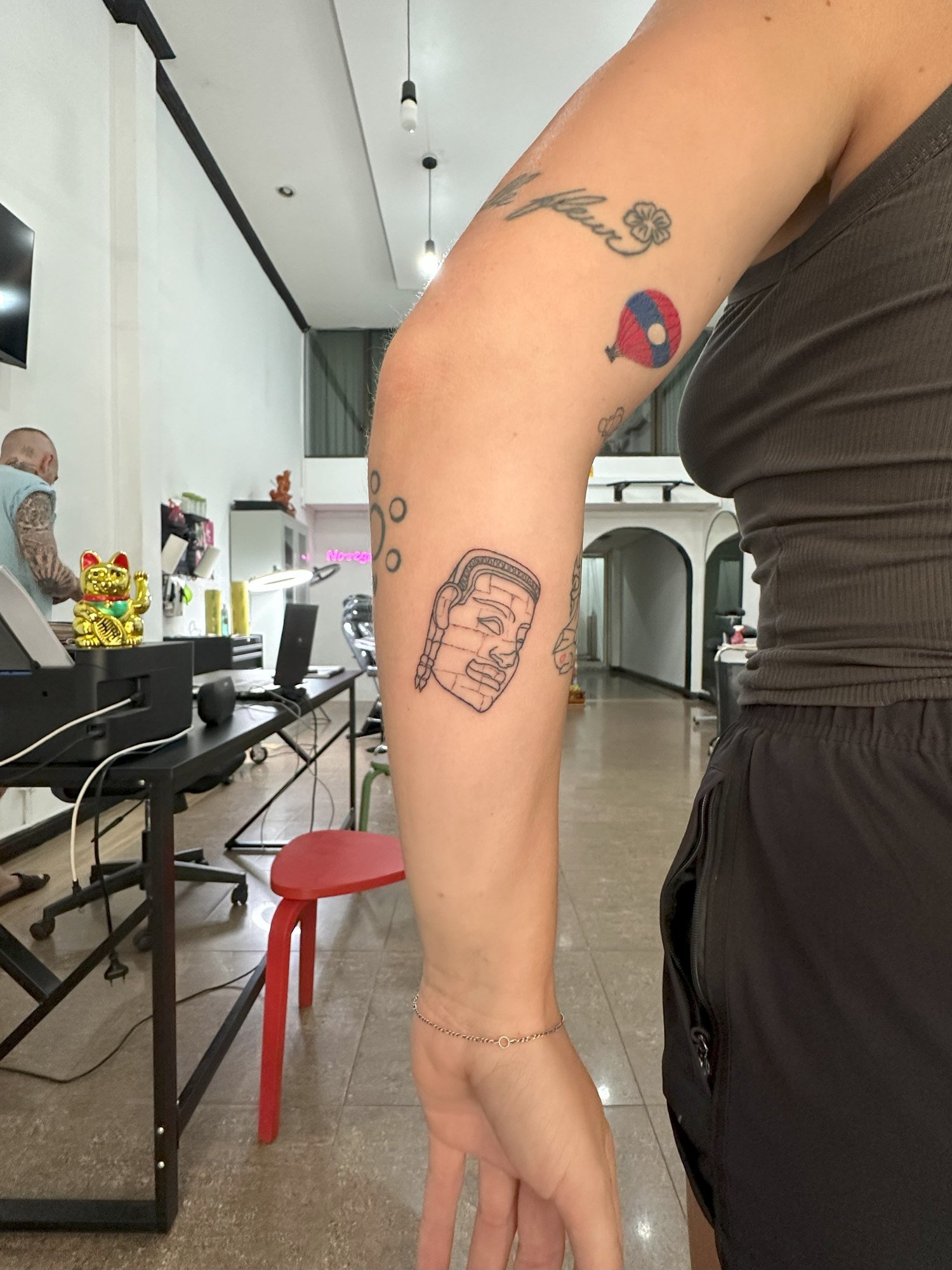 A stone temple face with block-like details outlined in black on the forearm. Tattoo by Edboi