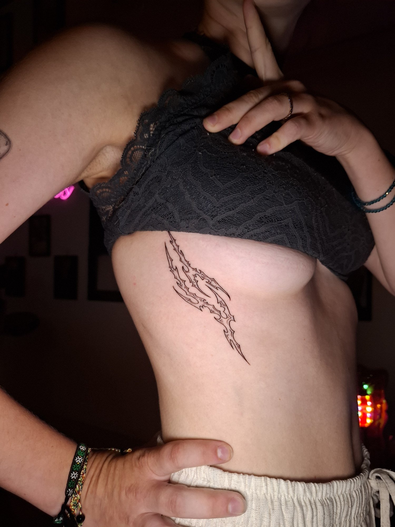 An elongated tribal design with sharp curves and delicate black outlines on the ribs. Tattoo by Edboi