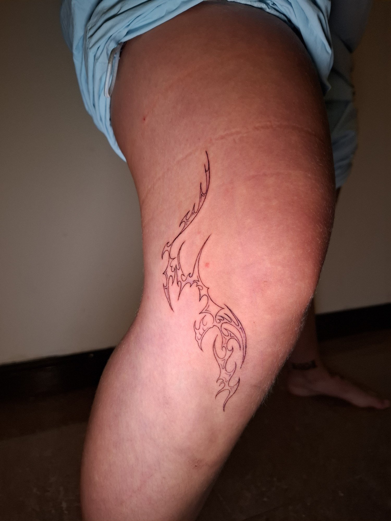 A flowing tribal composition with curved hooks and pointed black outlines on the thigh. Tattoo by Edboi