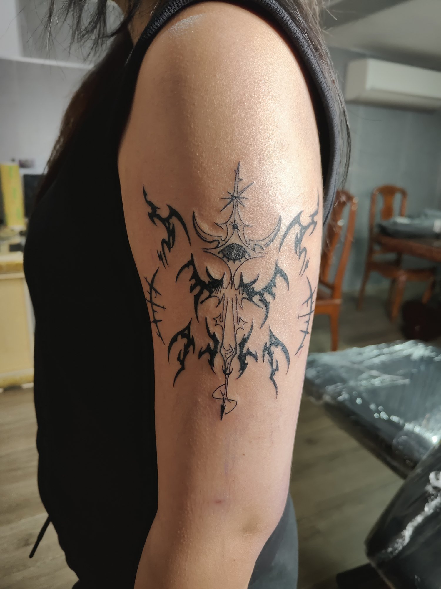 Sharp black tribal shapes with fine ornamental details on the upper arm. Tattoo by Edboi