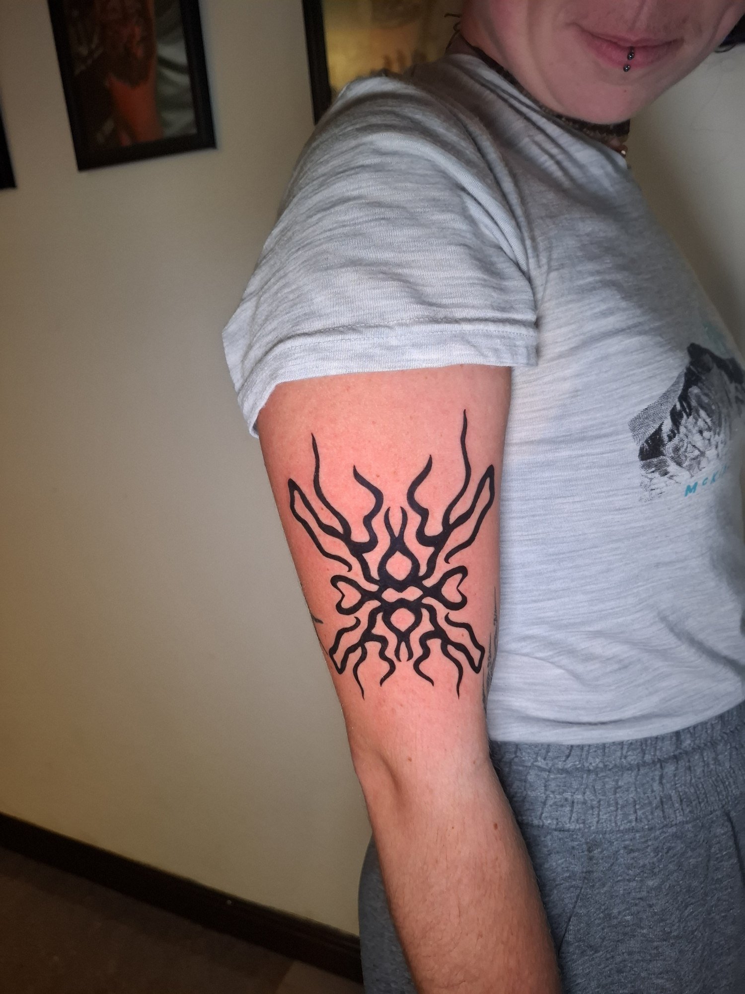 A bold sun-like tribal composition on the upper arm. Tattoo by Edboi